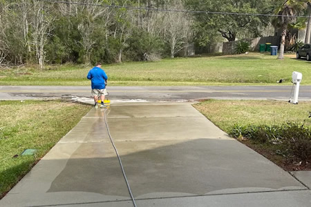 Technician using a surface cleaner to wash a concrete driveway in vancleave ms